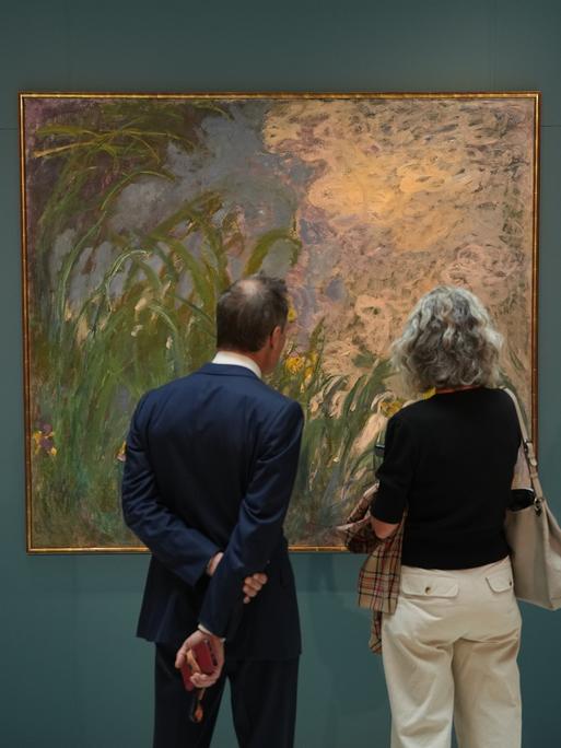 Zwei Personen stehen vor dem Gemälde „Iris“ von Claude Monet im Auktionshaus Sotheby’s in Paris.