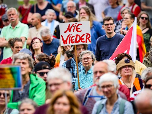 Demonstration gegen Rechts: Eine Frau hält ein Plakat hoch, auf dem "Nie wieder" steht.