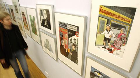 Eine Besucherin blickt im Wilhelm-Busch-Museum in Hannover auf Karikaturen, die an einer Wand hängen. Die Arbeiten gehören zu 391 ausgestellten Karikaturen, die von Zeichnerinnen und Zeichnern aus dem Umfeld der Satirezeitschrift "Eulenspiegel" stammen. Eine Besucherin blickt im Wilhelm-Busch-Museum in Hannover auf Karikaturen, die an einer Wand hängen. Die Arbeiten gehören zu 391 ausgestellten Karikaturen, die von Zeichnerinnen und Zeichnern aus dem Umfeld der Satirezeitschrift "Eulenspiegel" stammen.