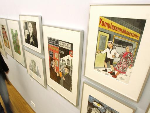 Eine Besucherin blickt im Wilhelm-Busch-Museum in Hannover auf Karikaturen, die an einer Wand hängen. Die Arbeiten gehören zu 391 ausgestellten Karikaturen, die von Zeichnerinnen und Zeichnern aus dem Umfeld der Satirezeitschrift "Eulenspiegel" stammen. 