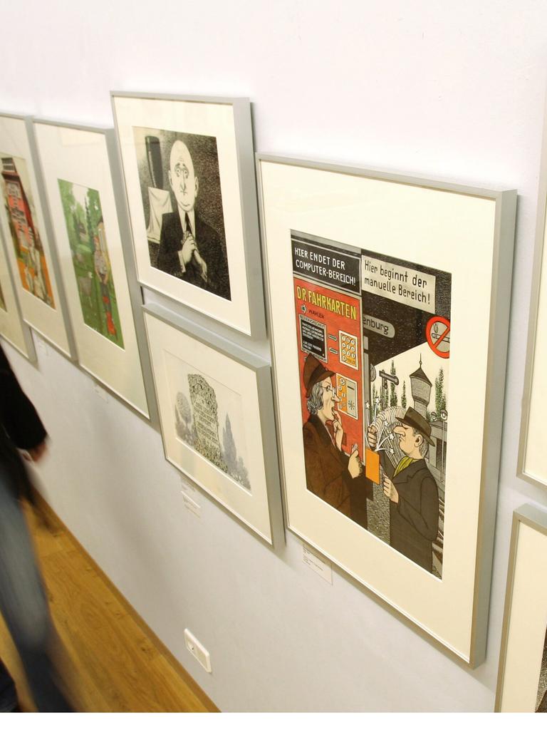 Eine Besucherin blickt im Wilhelm-Busch-Museum in Hannover auf Karikaturen, die an einer Wand hängen. Die Arbeiten gehören zu 391 ausgestellten Karikaturen, die von Zeichnerinnen und Zeichnern aus dem Umfeld der Satirezeitschrift "Eulenspiegel" stammen. 