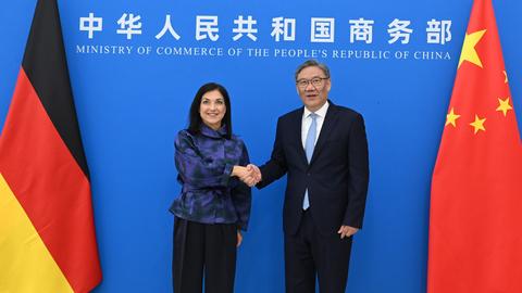Wirtschaftsministerin Katherina Reiche schüttelt die Hand von Chinas Handelsminister Wang Wentao. Im Hintergrund der Schriftzug von Wangs Ministerium sowie die Flaggen beider Länder.