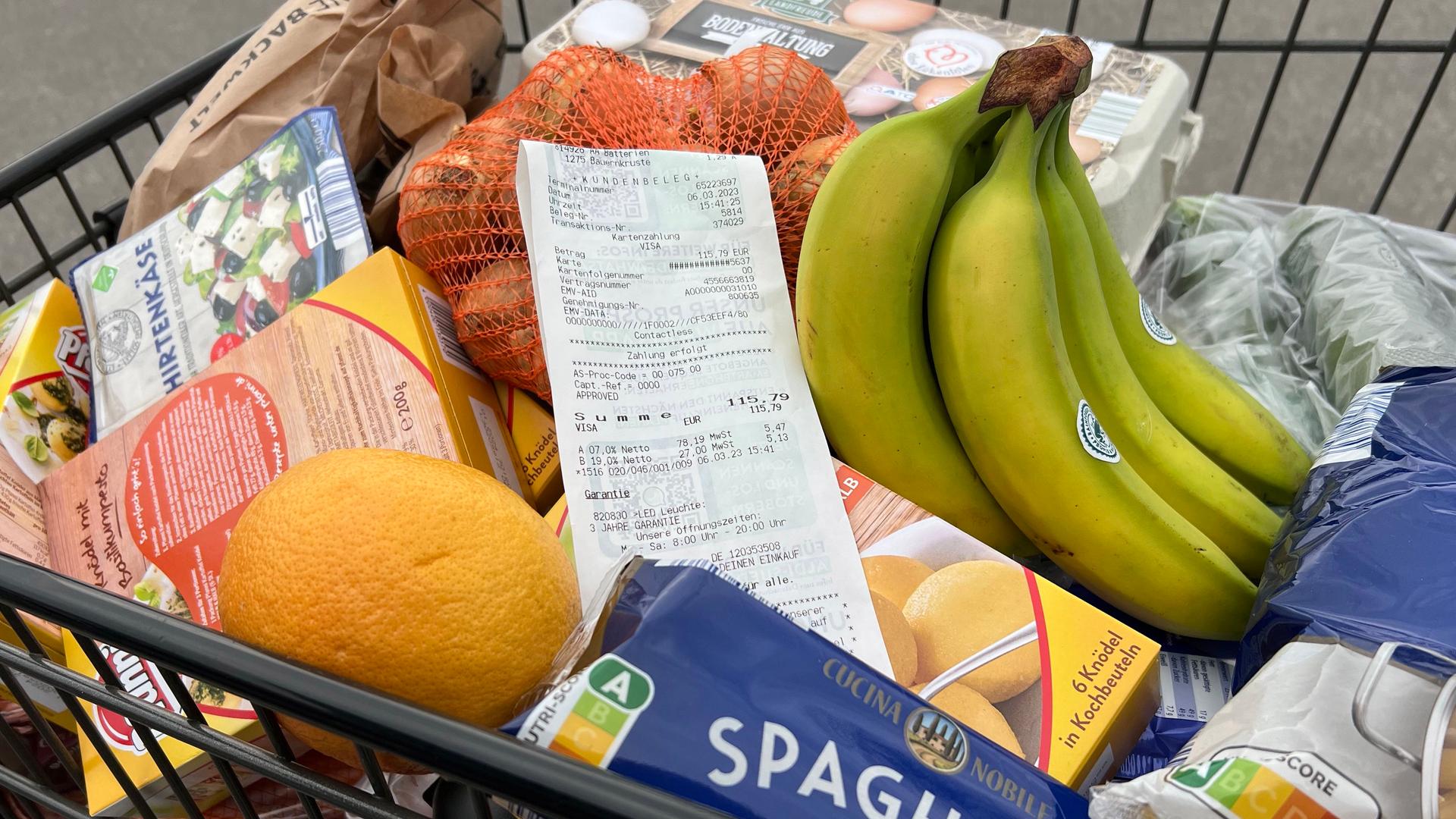 Blick in einen vollen Einkaufswagen mit Kassenbon.