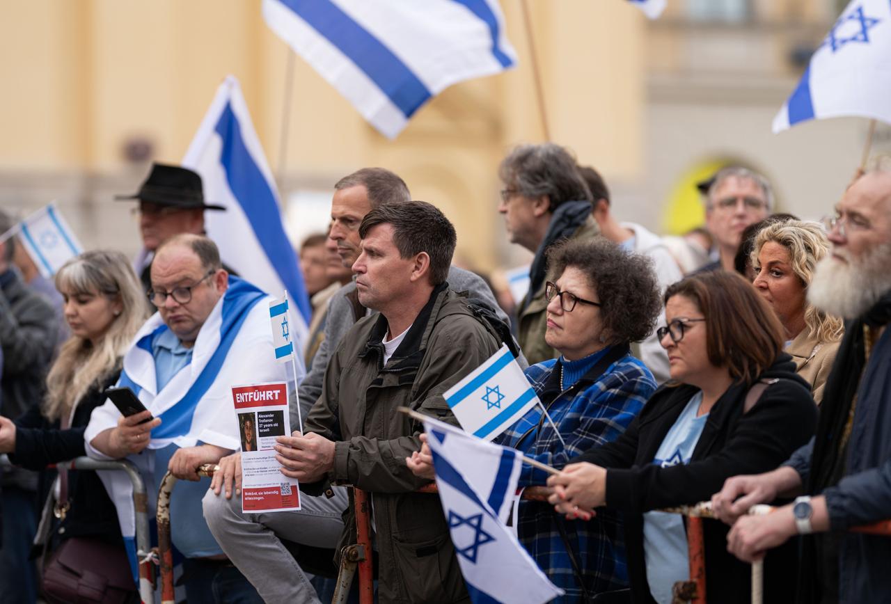 Teilnehmer der Kundgebung "Solidarität mit Israel - Gegen gegen Terror, Hass und Antisemitismus" halten israelische Fahnen in den Händen.