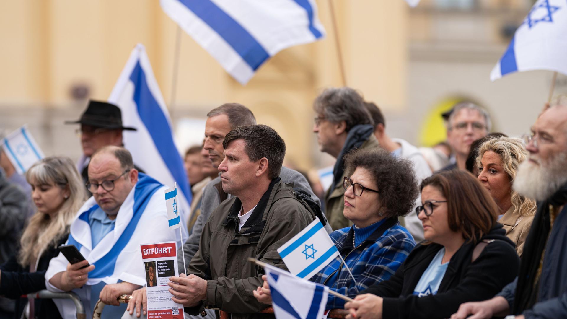 Teilnehmer der Kundgebung "Solidarität mit Israel - Gegen gegen Terror, Hass und Antisemitismus" halten israelische Fahnen in den Händen.
