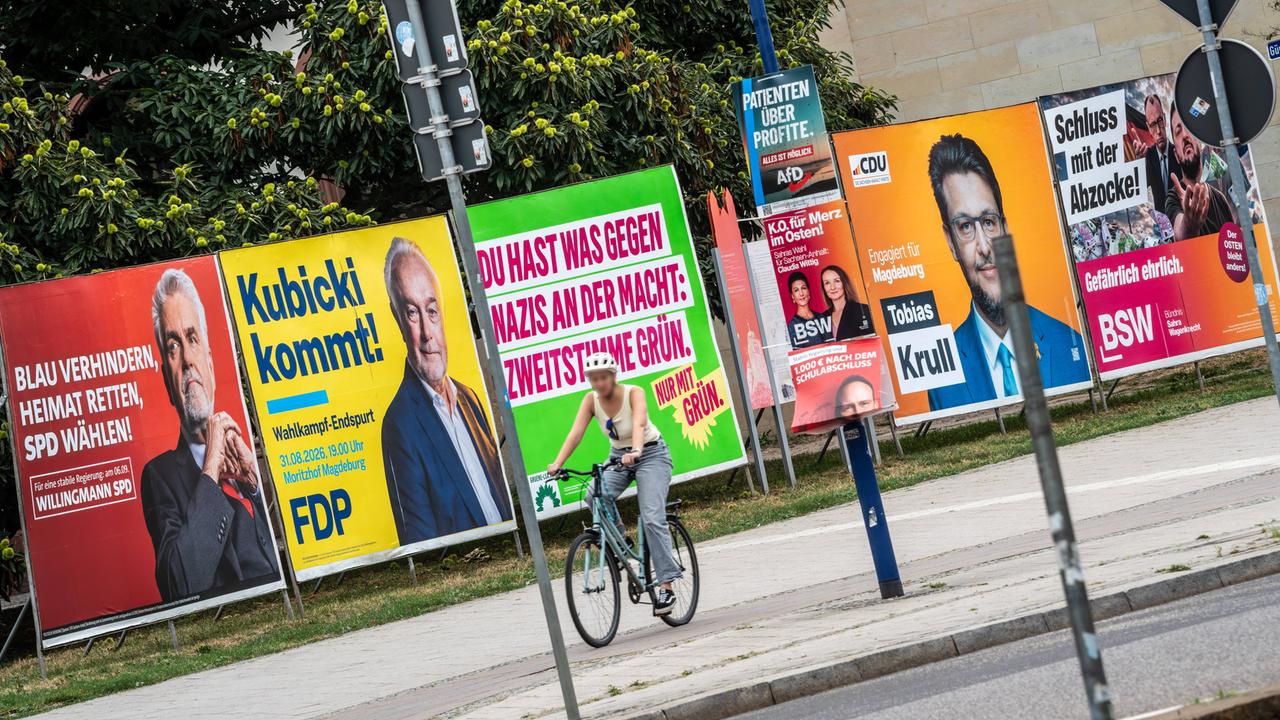 Eine Fahrradfahrerin fährt in Magdeburg an Wahlplakaten verschiedener Parteien vorbei.