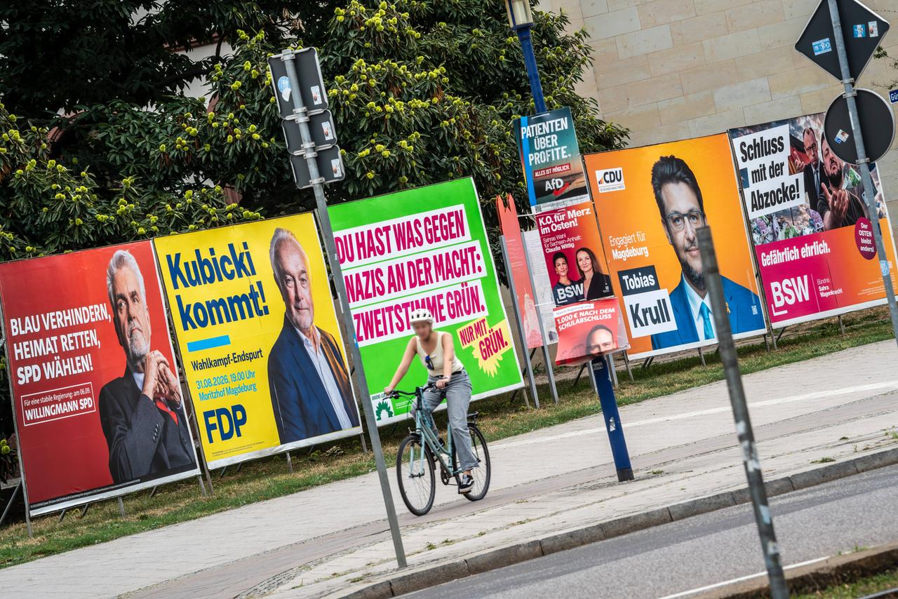 Eine Fahrradfahrerin fährt in Magdeburg an Wahlplakaten verschiedener Parteien vorbei.