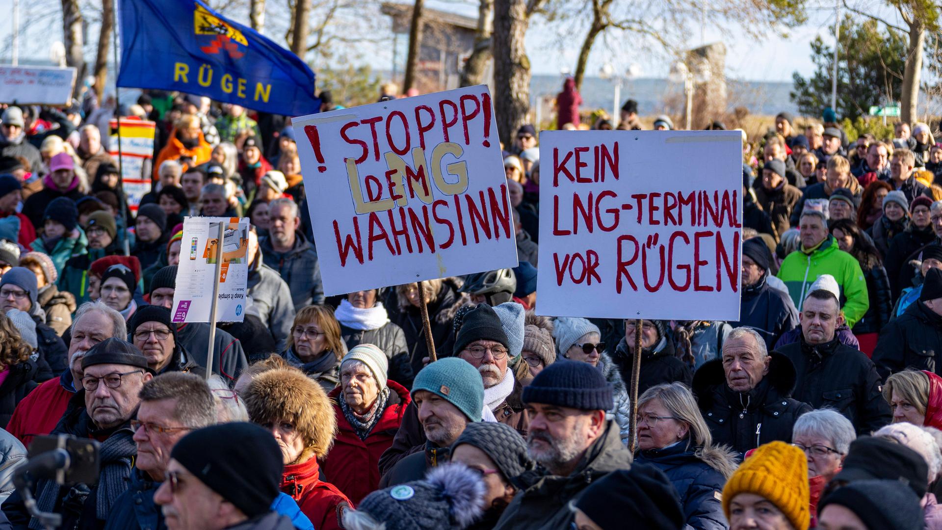 Demonstrierende auf Rügen halten Schilder hoch, auf denen steht "Kein LNG-Terminal vor Rügen" und "Stopp den LNG-Wahnsinn".