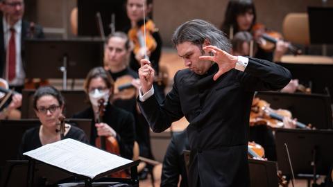 Der Dirigent Vladimir Jurowski steht mit offenen Haaren und kraftvoller Geste vor seinem Orchester.