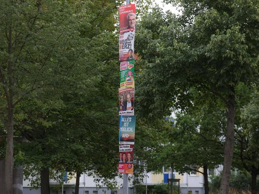 An einer Straßenlampe hängen untereinander verschiedene Wahlplakate zur Landtagswahl 2026 in Sachsen-Anhalt.