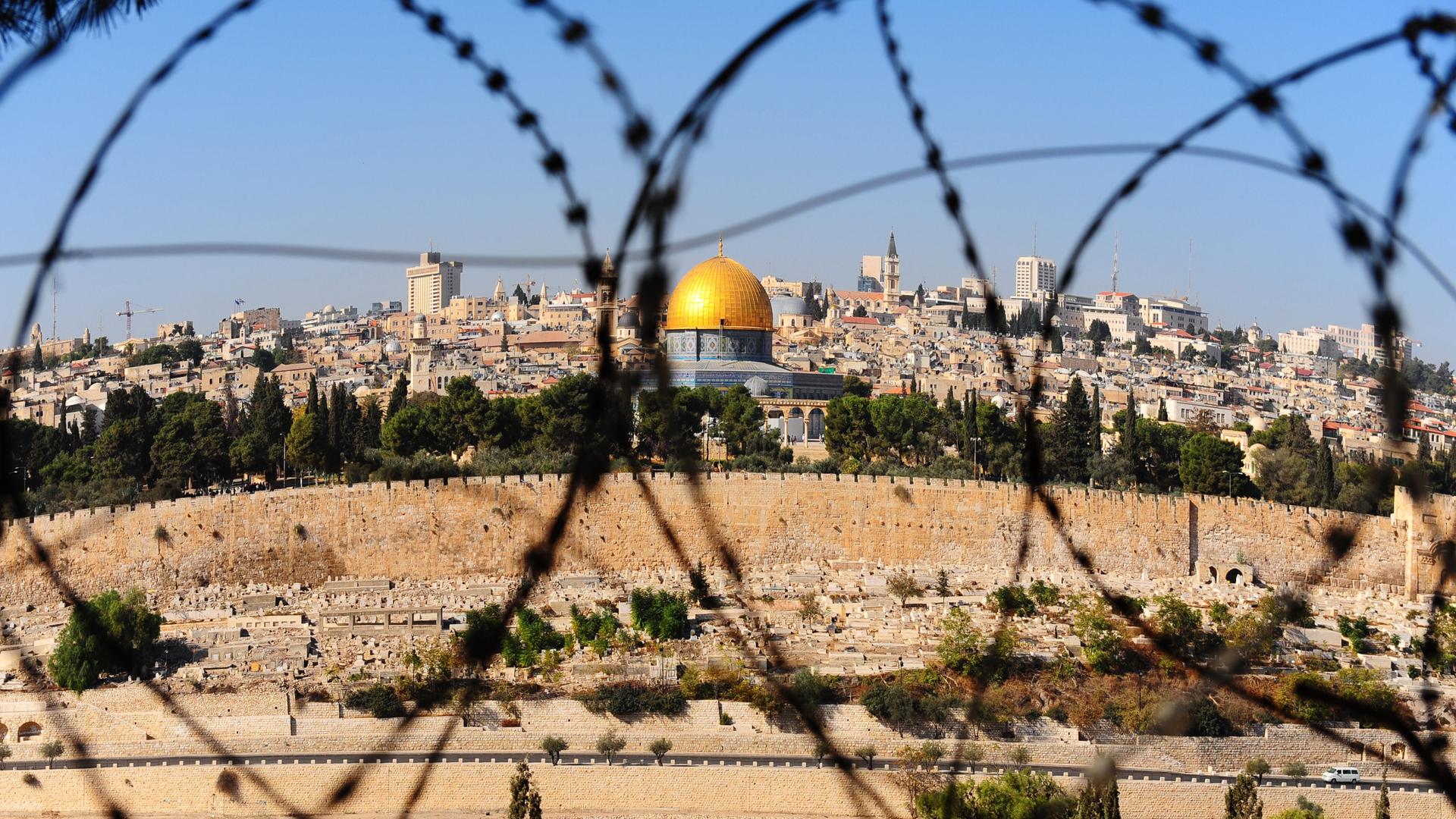 View from the Mount of Olives on the dome of the rock and ancient cemetery through the barbed wire, as a symbol of Palestine Israeli conflict View from the Mount of Olives on the dome of the rock and ancient cemetery through the barbed wire, as a symbol of Palestine Israeli conflict