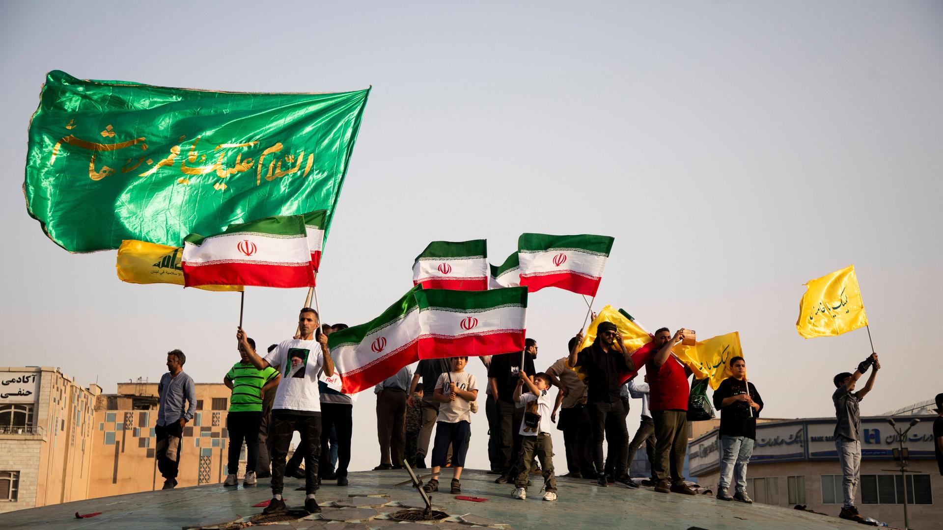 Menschen in Teheran feiern mit iranischen Flaggen und Postern, die das geistliche Oberhaupt des Landes, Ayatollah Ali Chamenei, zeigen, den Waffenstillstand mit Israel.