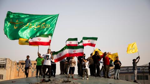 Menschen in Teheran feiern mit iranischen Flaggen und Postern, die das geistliche Oberhaupt des Landes, Ayatollah Ali Chamenei, zeigen, den Waffenstillstand mit Israel.