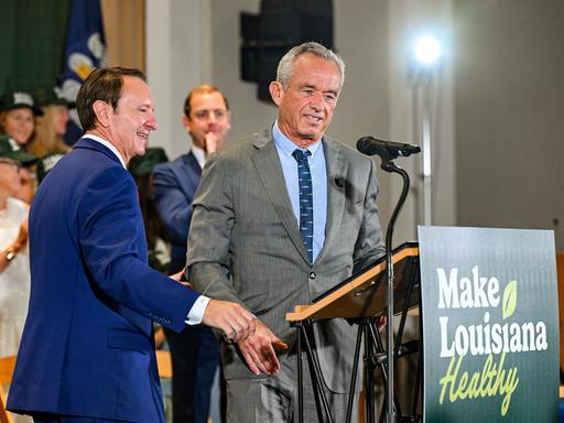 Robert F. Kennedy Jr. (r.) steht an einem Rednerpult. An dem Pult ist ein Schild mit der Aufschrift "Make Louisiana Healthy" befestigt.