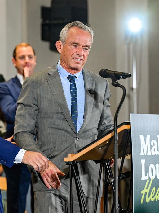 Robert F. Kennedy Jr. (r.) steht an einem Rednerpult. An dem Pult ist ein Schild mit der Aufschrift "Make Louisiana Healthy" befestigt.