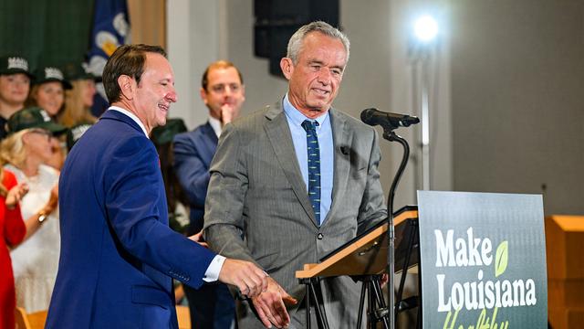 Robert F. Kennedy Jr. (r.) steht an einem Rednerpult. An dem Pult ist ein Schild mit der Aufschrift "Make Louisiana Healthy" befestigt.