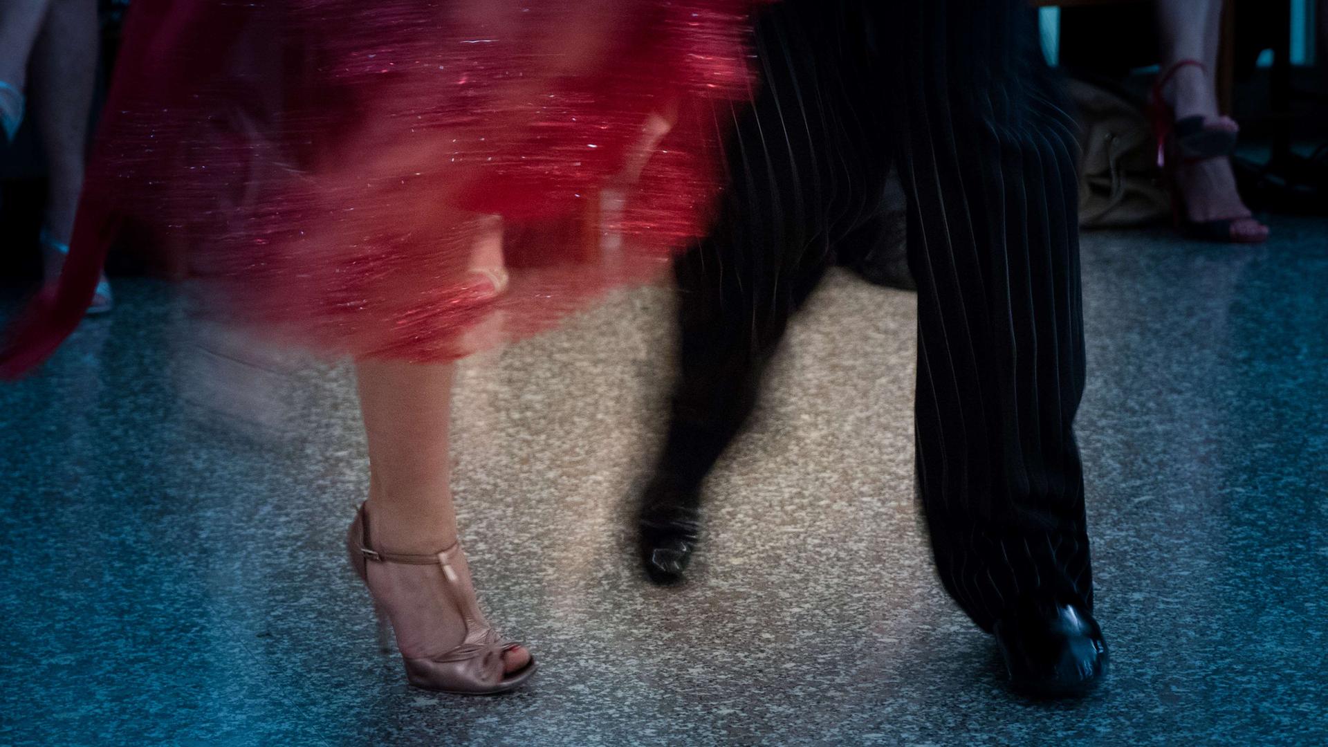 Verwackeltes Foto der Füße und Beine eines Tango tanzenden Paars.