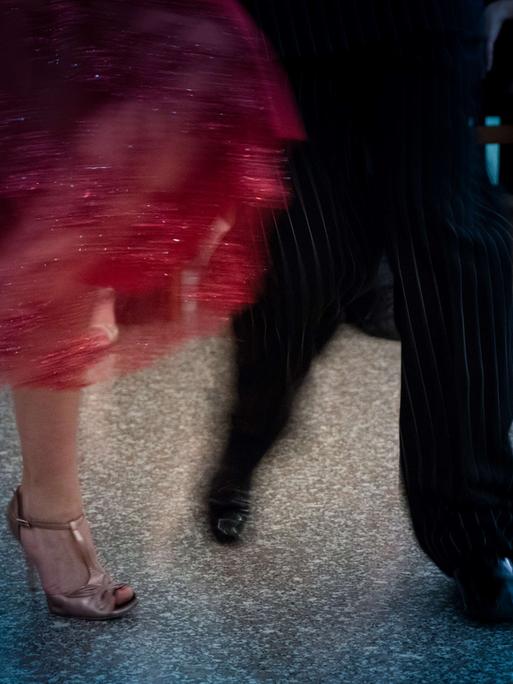 Verwackeltes Foto der Füße und Beine eines Tango tanzenden Paars.