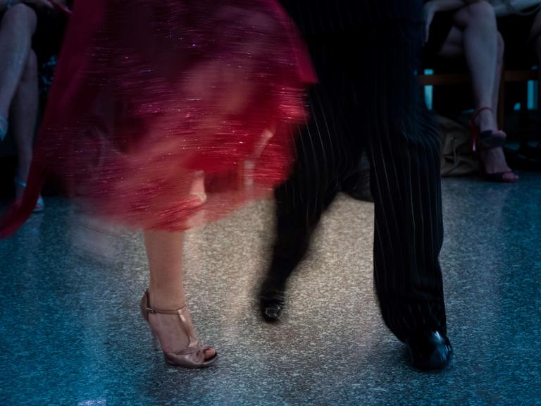 Verwackeltes Foto der Füße und Beine eines Tango tanzenden Paars.