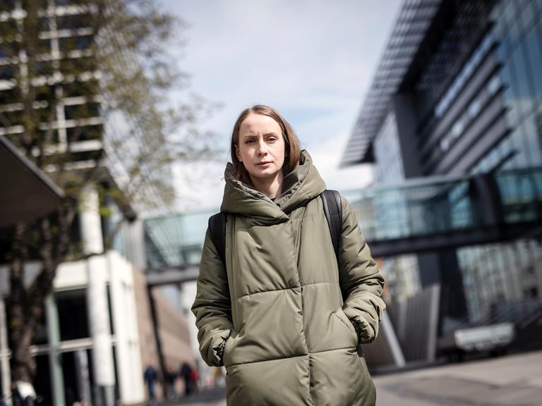 Anastasiia Kosodii in einem langen Mantel auf der Straße.