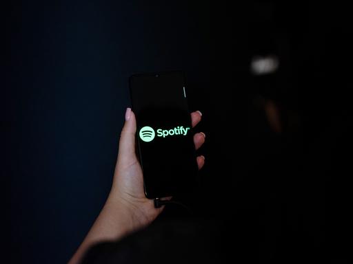 Eine Hand hält ein Smartphone mit dem Spotify Logo auf dem Display.
