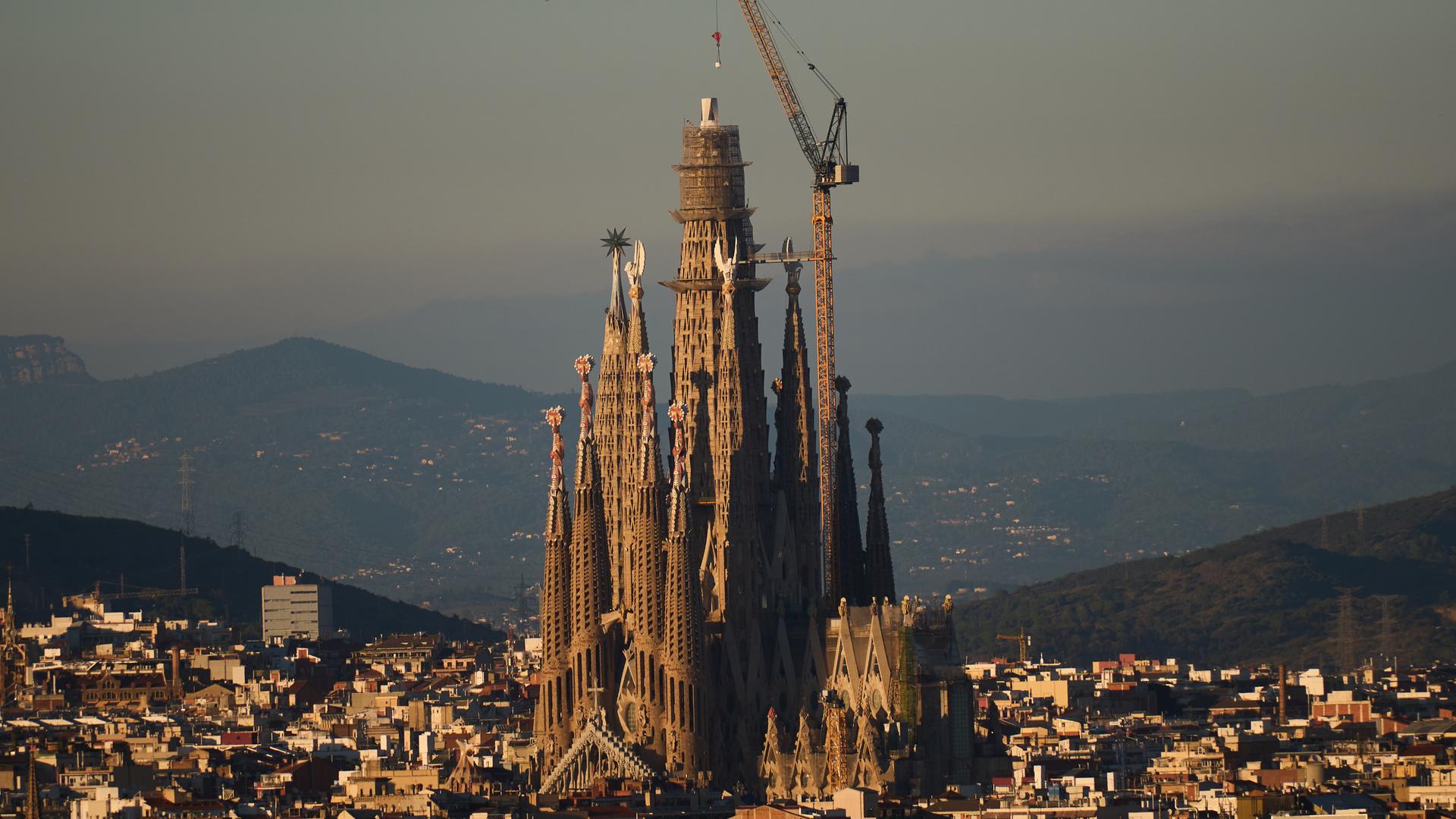 Blick auf die Basilika Sagrada Familia. Ein Kran setzt das Kreuzsegment auf die Spitze des Turms. Blick auf die Basilika Sagrada Familia. Ein Kran setzt das Kreuzsegment auf die Spitze des Turms.