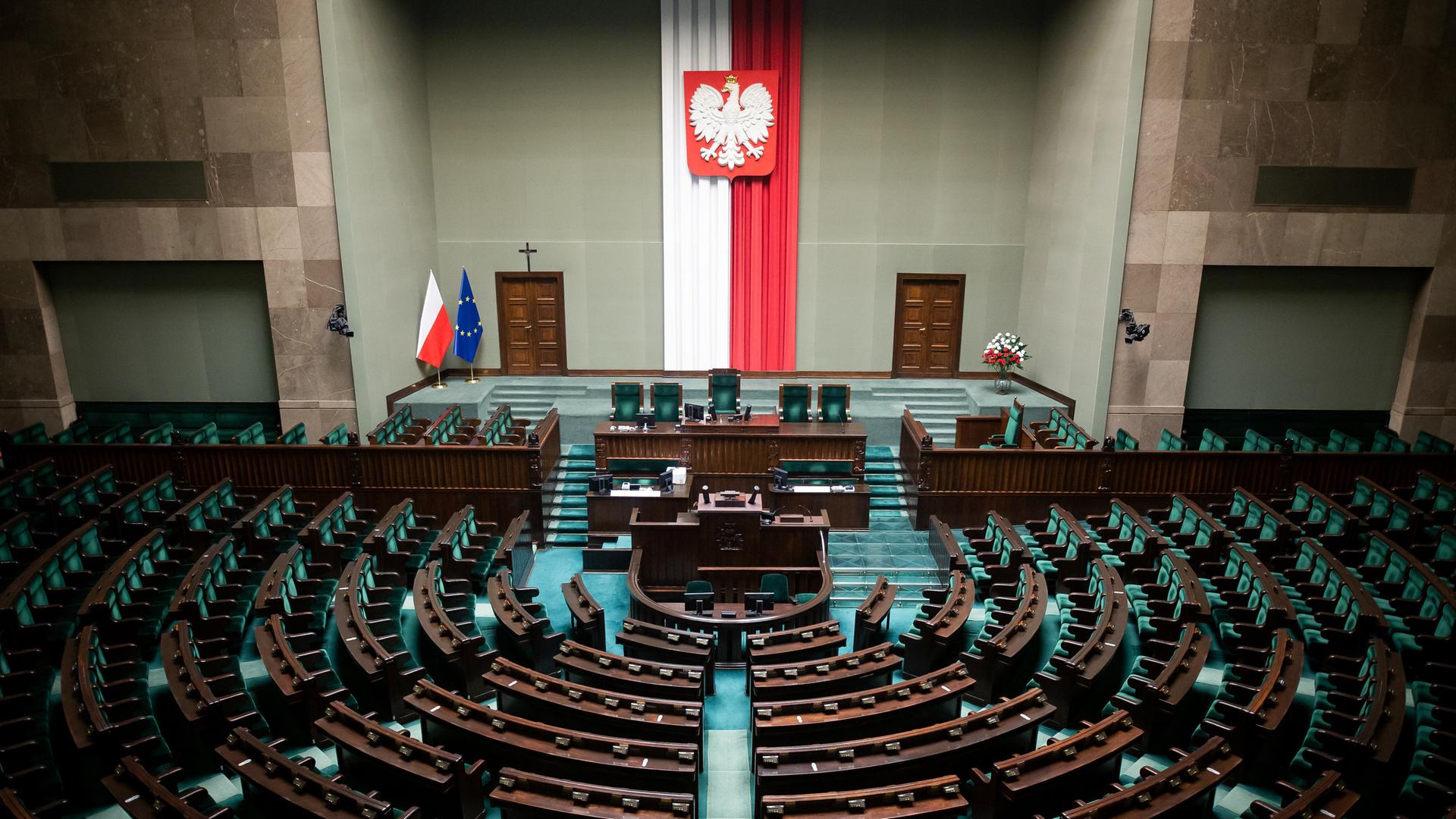 Blick von der Zuschauertribüne auf die leeren Reihen des Parlaments. An der Wand hängt eine längliche polnische Fahne.