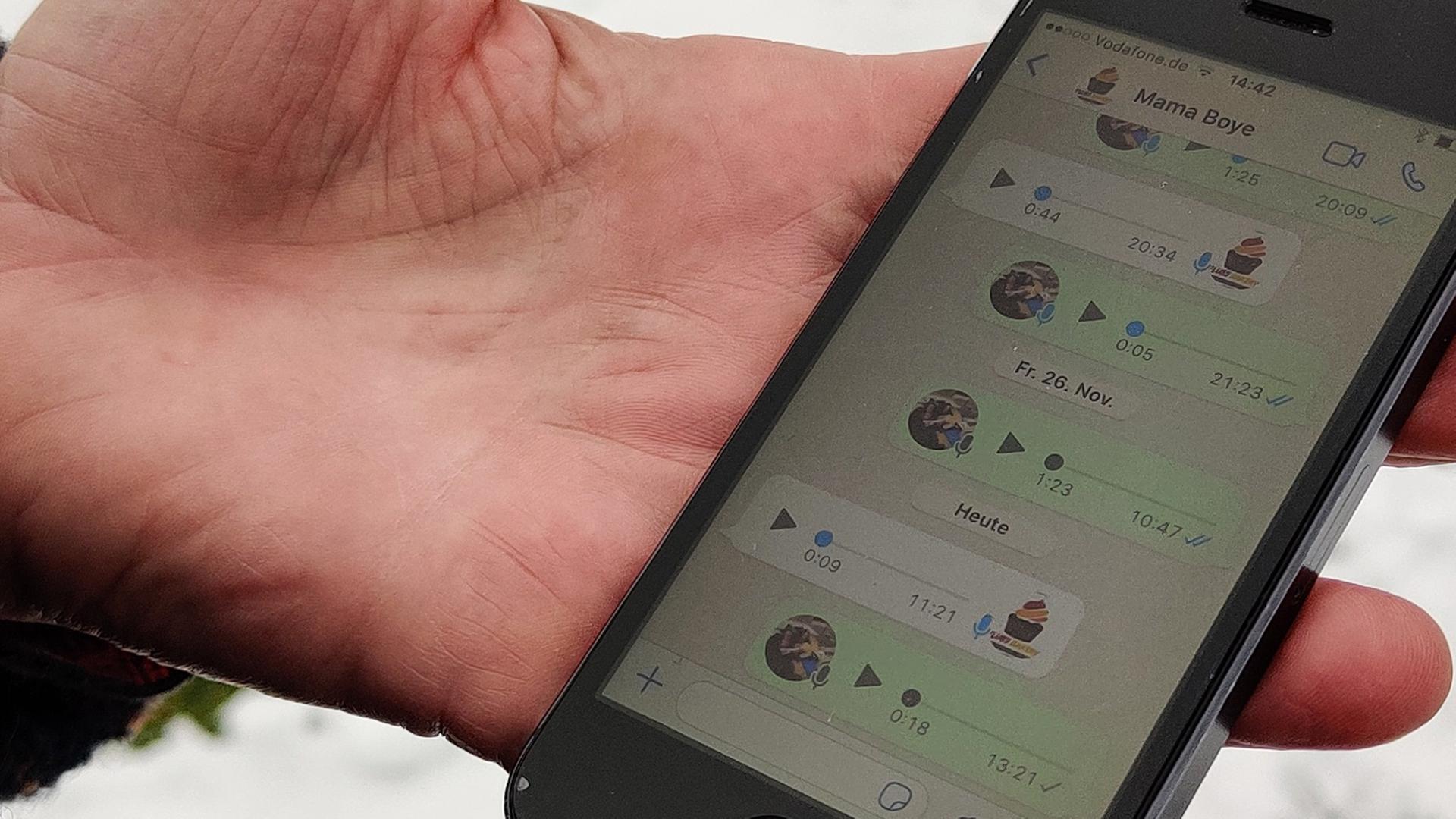 Eine Hand hält ein Smartphone, auf der man einen Whatsapp-Chat sehen kann. 