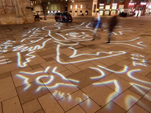 Eine LIchtgrafik der Künstlerin Gabriele Stötzer bedeckt mit Linien und Kringeln den Boden eines Platzes. 