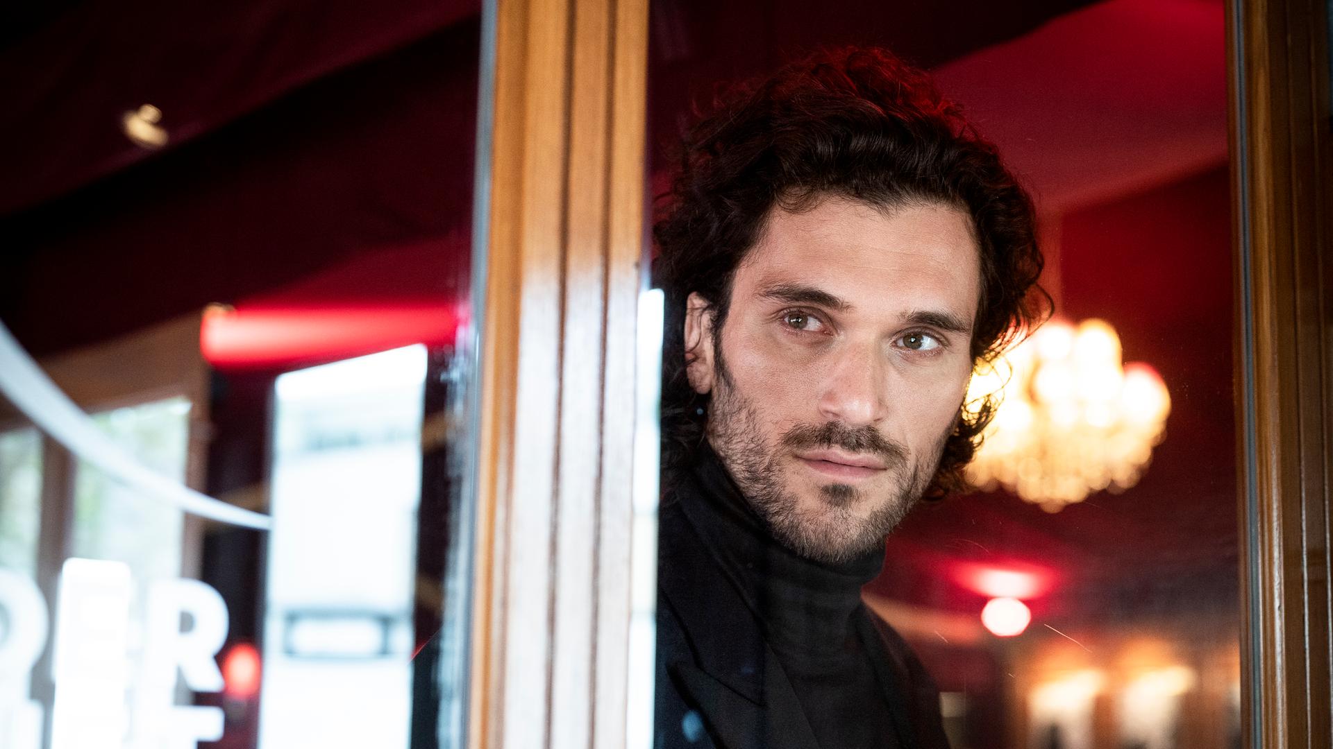 Sänger Vladimir Korneev schaut aus einem Fenster in der Bar jeder Vernunft in Berlin, im Hintergrund sieht man verschwommen einen Kronleuchter. Sänger Vladimir Korneev schaut aus einem Fenster in der Bar jeder Vernunft in Berlin, im Hintergrund sieht man verschwommen einen Kronleuchter.