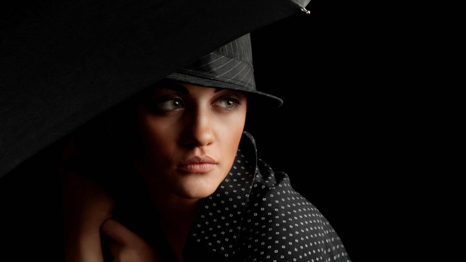 Bild in Schwarztönen: Elegante Frau mit Hut und Schirm im Stil der 1930er Jahre in Chicago, mysteriöser Blick.