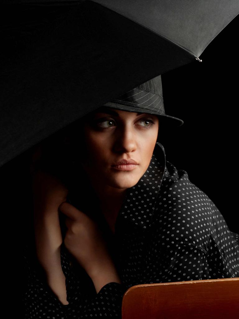 Bild in Schwarztönen: Elegante Frau mit Hut und Schirm im Stil der 1930er Jahre in Chicago, mysteriöser Blick.