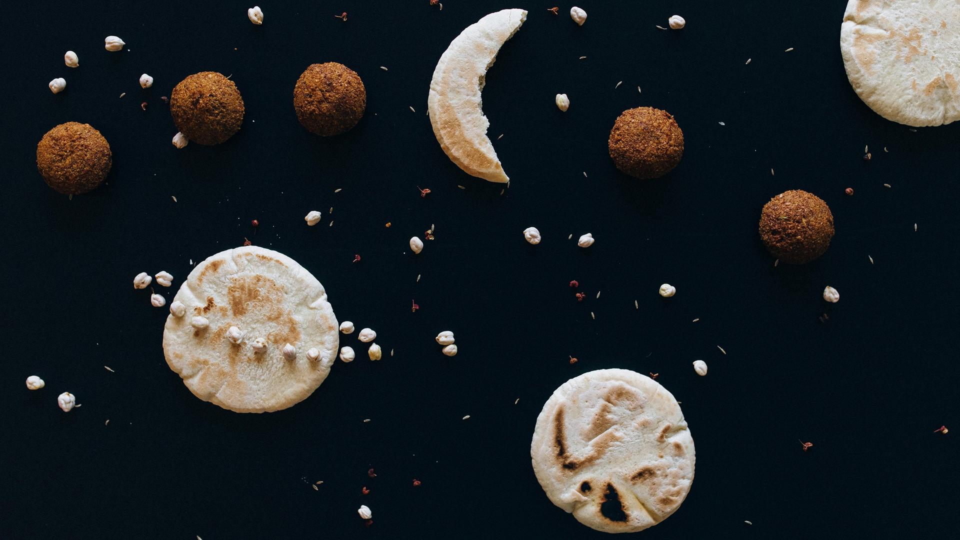 Auf einem dunklen Untergrund liegen diverse Kekse und Nüsse, die den Weltraum mit Monden und Planeten darstellen.