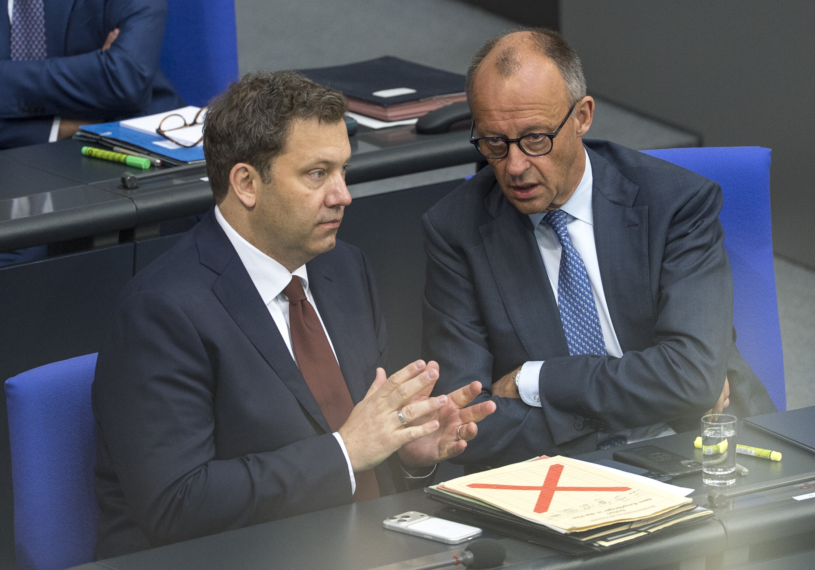 Bundesfinanzminister Lars Klingbeil (links) und Bundeskanzler Friedrich Merz /CDU) sitzen am 11.06.2026  im  Bundestag. Merz erzählt Klingbeil offenbar etwas. Beide wirken angespannt.