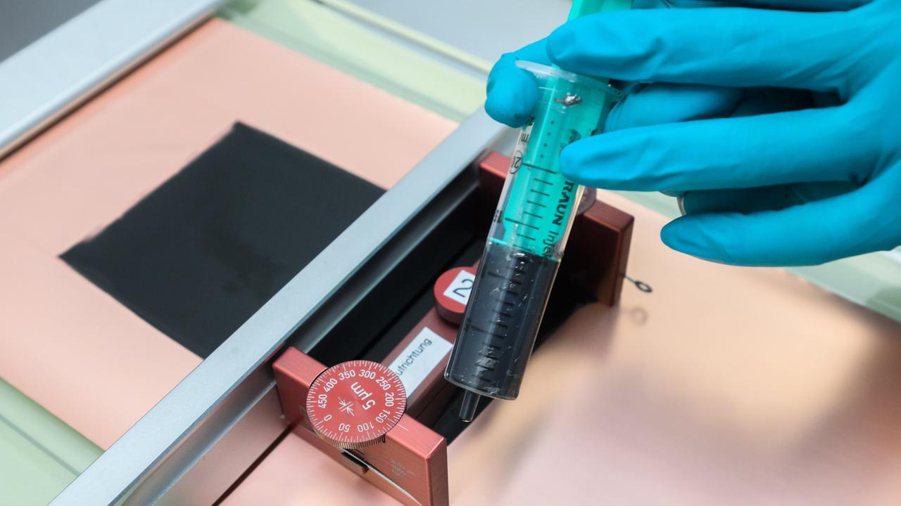Eine Mitarbeiterin bringt im Labor für Zellforschung und Entwicklung im VW-Werk Salzgitter mit einer Spritze Batteriesuspension auf einer Stomableiterfolie auf und fertigt damit eine Elektrode.