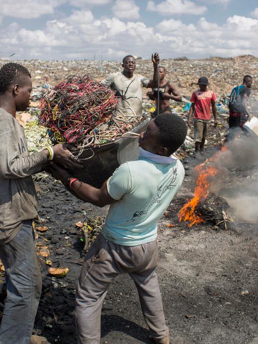 Junge afrikanische Männer verbrennen Elektroschrott auf der grössten Elektromülldeponie Afrikas in Agbogbloshie, einem Stadtteil von Ghanas Hauptstadt. Hier verbrennt man ausgediente Altgeräte, um an verwertbares Metall zu kommen. 