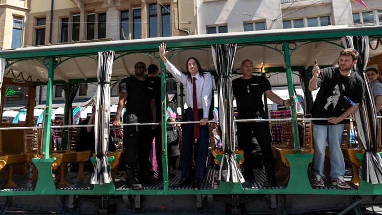 Mehrere Männer stehen in einer Oldtimer-Straßenbahn. Der Mann in der Mitte winkt. Mehrere Männer stehen in einer Oldtimer-Straßenbahn. Der Mann in der Mitte winkt.