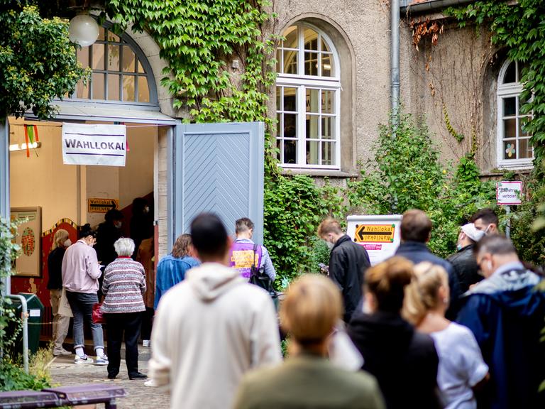 Viele Menschen stehen in Berlin vor einem Wahllokal, das in einer Grundschule untergebracht ist.