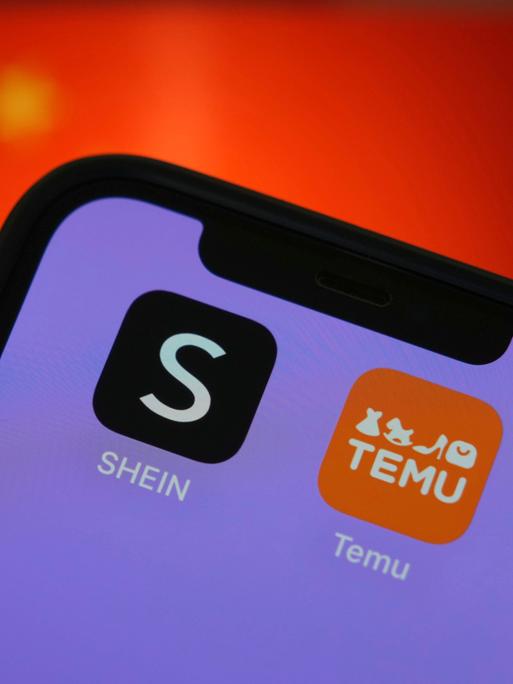 Die App-Logos der Online-Billighändler Temu und Shein sind auf einem Smartphon zu sehen. Im Hintergrund ist die chinesische Flagge unscharf angedeutet.