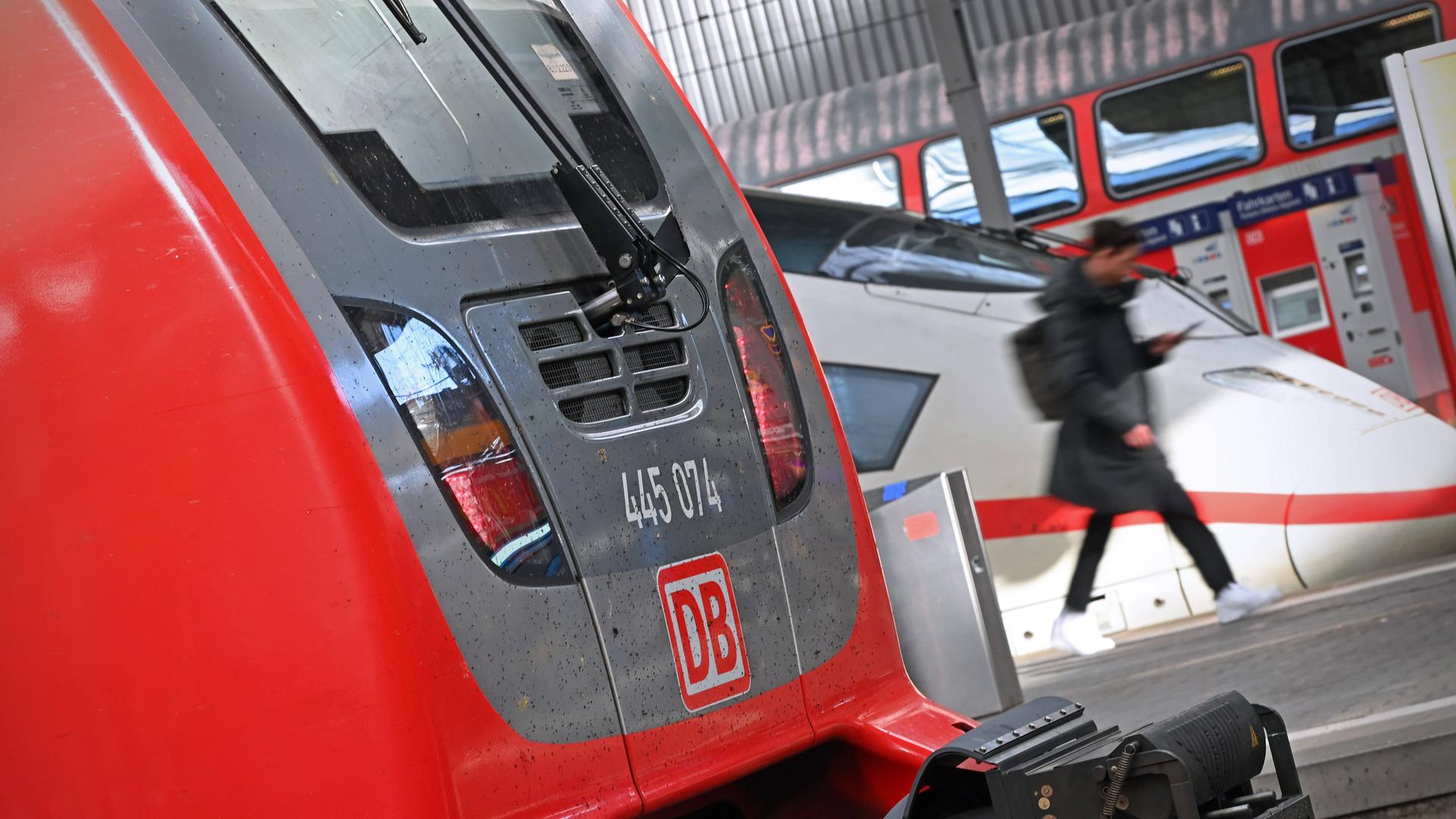 Während des Bahnstreiks läuft ein Passagier im Hauptbahnhof München auf dem Bahnsteig auf sein Handy blickend zwischen zwei Loks hindurch.   
