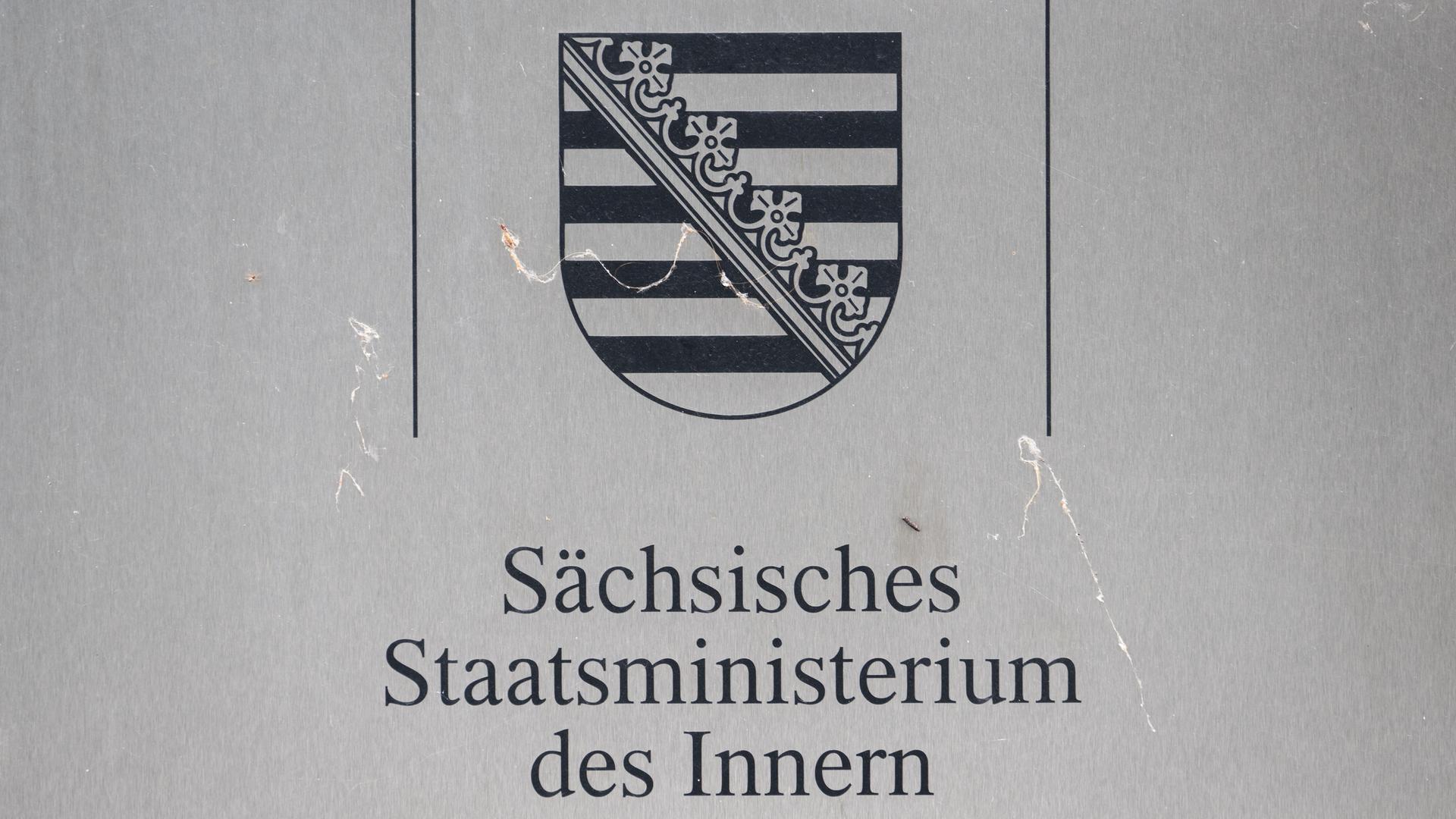 Ein Schild „Sächsisches Staatsministerium des Inneren“ ist am Eingang des Gebäudes unter dem Wappen vom Freistaat Sachsen angebracht.