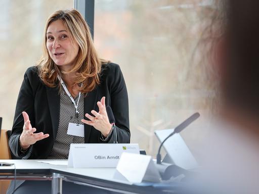 Constance Arndt, Oberbürgermeisterin von Zwickau. Sie sitzt gestikulierend an einem Tisch. 