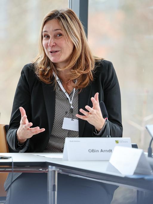 Constance Arndt, Oberbürgermeisterin von Zwickau. Sie sitzt gestikulierend an einem Tisch. 