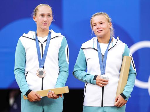 Die russischen Tennisspielerinnen Mirra Andreeva und Diana Shnaider tragen bei der Medaillenzeremonie die Kleidung der neutralen individuellen Athlet:innen.