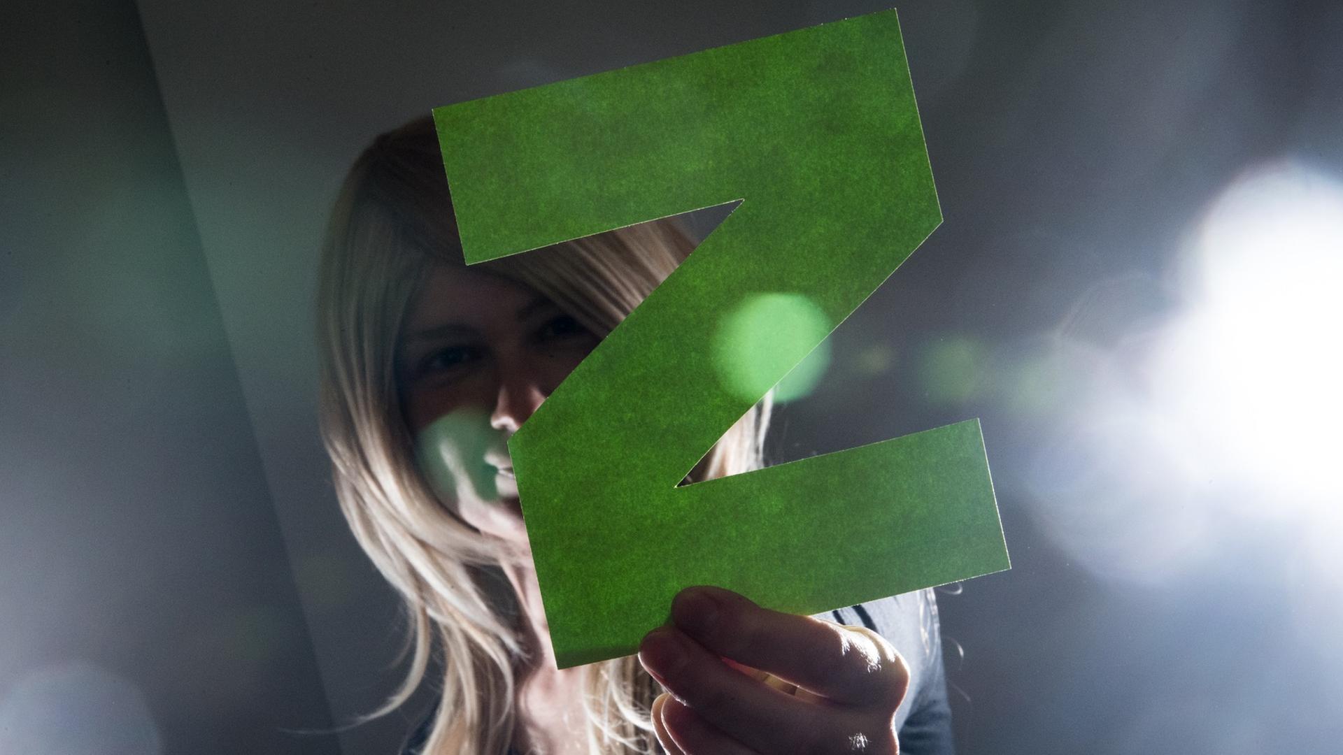 Eine junge Frau hält ein großes "Z" in die Kamera.