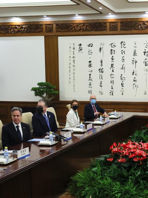US-Außenminister Antony Blinken sitzt in Peking mit der amerikanischen und der chinesischen Delegation an Konferenztischen.