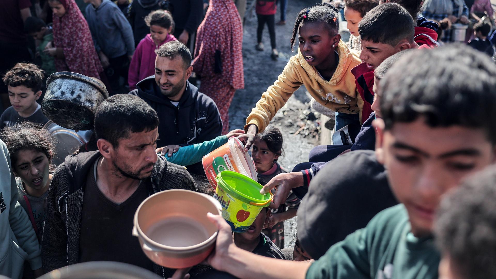 Menschen stehen im Gazastreifen bei einer Essensausgabe an.