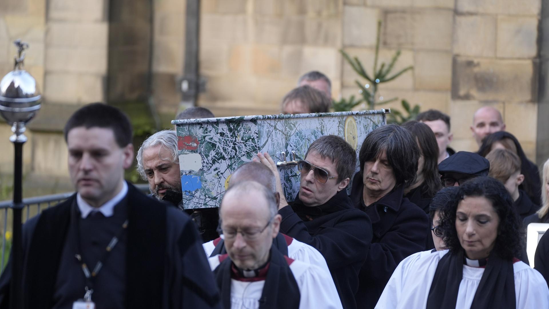 Alan Wren, links, Liam Gallagher, rechts, und John Squire, zweiter von rechts, tragen Gary 'Mani' Mounfields Sarg. 