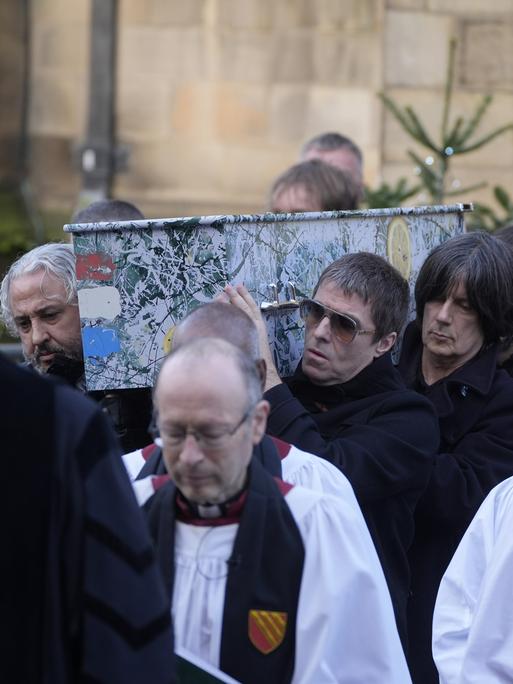 Alan Wren, links, Liam Gallagher, rechts, und John Squire, zweiter von rechts, tragen Gary 'Mani' Mounfields Sarg. 