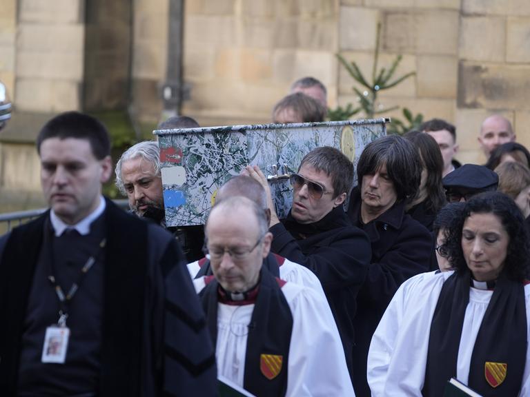 Alan Wren, links, Liam Gallagher, rechts, und John Squire, zweiter von rechts, tragen Gary 'Mani' Mounfields Sarg. 